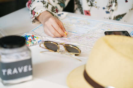 women holding paper pin and push pin on the map ,planning a trip by searching the route on smartphone on desk.の写真素材