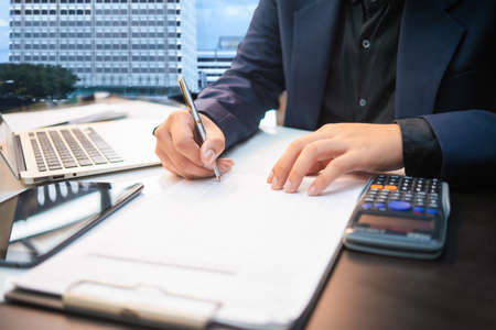 Business man working on desk office ,writing make note and using a calculator at home office. finance accounting conceptの写真素材