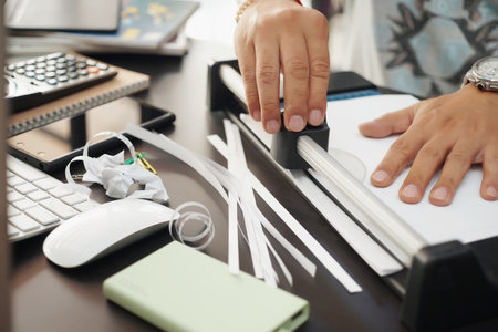 office man using manual paper cutter or paper trimmer tool cutting white paper on black table .の写真素材