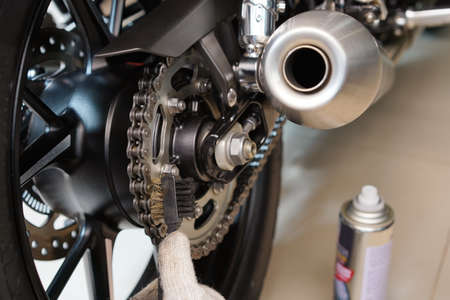Mechanic using Brass brush Clean and Maintain Motorcycle Chain and Sprockets, maintenance,repair motorcycle concept in garage .selective focusの写真素材
