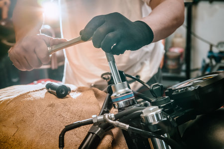 Mechanic using a wrench and socket on motorcycle in garage .maintenance,repair motorcycle concept .selective focusの写真素材