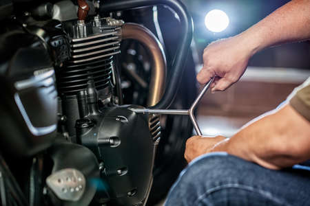 mechanic repairing motorcycle using wrench or socket on the engine of  motorcycle , maintenance,repair motorcycle concept in garageの写真素材