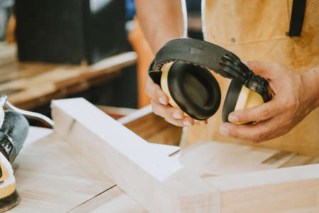 carpenter holding Protective ear muffs in the workshop ,DIY maker and woodworking concept. selective focusの写真素材