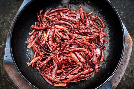 dried red chillies in a pan over a charcoal stoveの写真素材