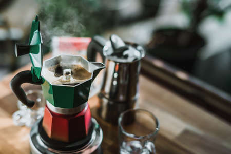 Hot coffee In Moka Pot on electric stove ,vintage coffee maker on wooden table at home, Selective focus.の写真素材