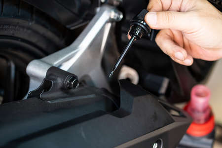 mechanic check engine oil level on scooter ,motorcycle in garage .motorcycle repair, maintenance and service conceptの写真素材