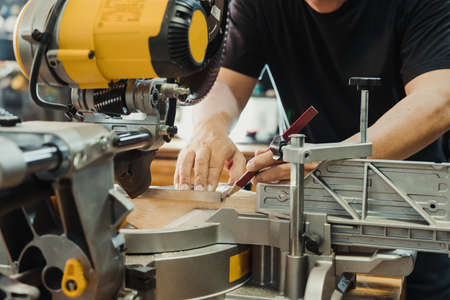 carpenter use machinist square and pencil marking on the wood on Miter saw table at work shop,DIY...