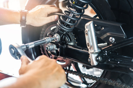 Mechanic using a wrench and socket to Remove and Replace Adjustable Rear Motorcycle Suspension, working in garage maintenance, repair motorcycle concept .selectiveの写真素材