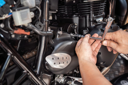 Mechanic using a Y Shape Wrench to Remove front sprocket cover on motorcycle, working in garage .maintenance and repair motorcycle concept .selective focusの写真素材