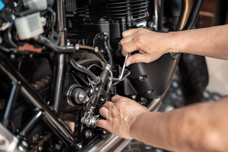 Mechanic using a Hex key or Allen wrench to remove Motorcycle rear Hydraulic brake pump, working in garage .maintenance and repair motorcycle concept .selective focusの写真素材