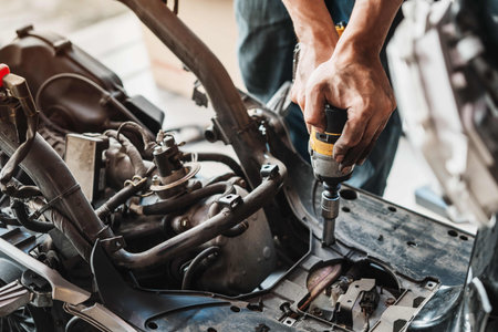 Motorcycle mechanic uses electric screwdriver ,power tool to repair motorcycle in garage.Maintenance and repair conceptの写真素材