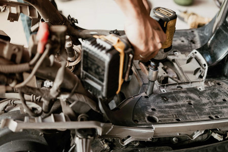 Motorcycle mechanic uses electric screwdriver to repair motorcycle in garage,Maintenance and repair...