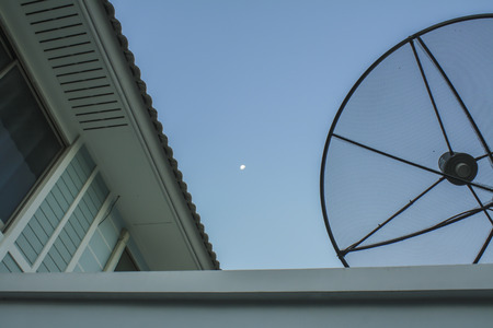 Satellite dish on the roof,blue sky with part of the moonの写真素材