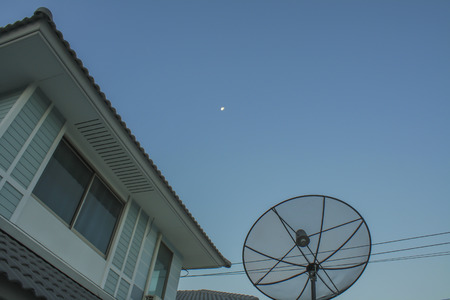 Satellite dish on the roof,blue sky with part of the moonの写真素材