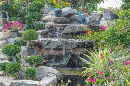 Stone garden with waterfalls and flowers pot decoration in cozy home flower garden on summer.の写真素材