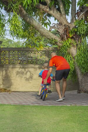 Asian father and children, teach to ride bicycles, spend time at home, Dad teach son to ride bike, father's day conceptの写真素材