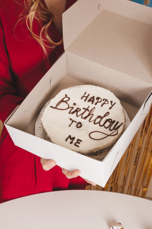 Beautiful girl with a cake at her birthday party. Blonde girl with flowers on the background of decorations for birthday celebrationの写真素材