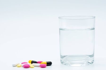 A glass of water with a pill on a white background