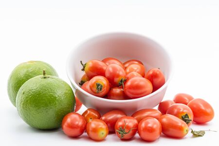 Fresh lime and tomato in a white bowl on a white backgroundの写真素材