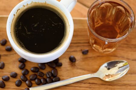 Black coffee and hot tea on a wooden table with coffee beans and a spoonの写真素材