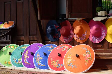 Handmade umbrellas and colorful hats against the wooden house backgroundの写真素材