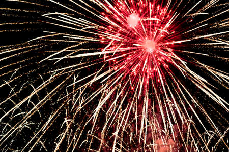 Close-up fireworks explode in the sky with motion blur on a black background.