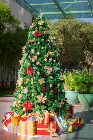 Christmas tree decorated with colorful ornaments and gift boxes.の写真素材