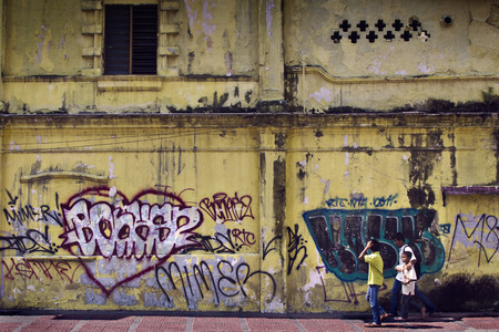 teenagers passing by a graffiti wall in Kuala Lumpurのeditorial素材