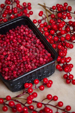 High quality photo about red frozen berries lie in a black dish on a wooden table side viewの写真素材