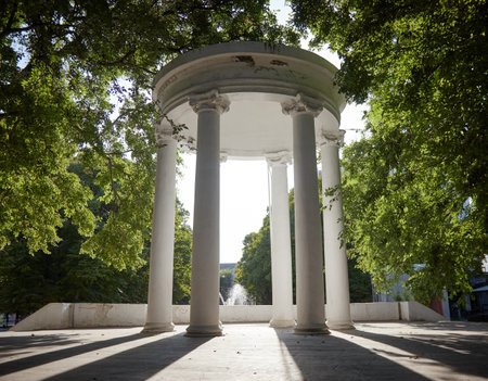 White stone gazebo with a round roof in the park view from below opposite the sunの写真素材