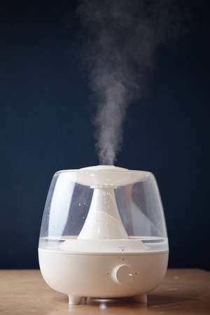 the white steam generator on the table is standing running emits steam view from afar from the sideの写真素材