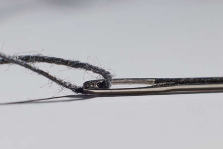 sewing needle with thread inside on the table macro photo blurred backgroundの写真素材