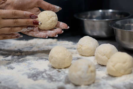 woman chef preparing dough makes the cheesecakes in the kitchen close up blurred backgroundの写真素材
