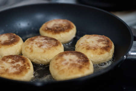 cheesecakes are fried in a frying pan the cook turns the dough with a spoon close up the background is blurredの写真素材
