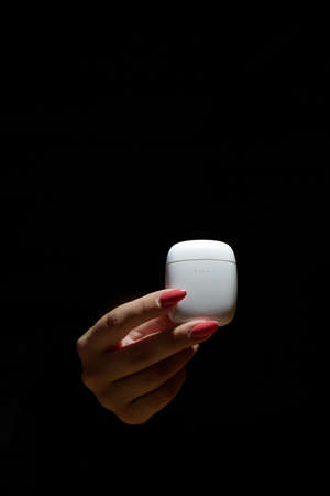 a womans hand holds a case for wireless headphones the background is blurredの写真素材