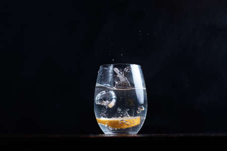 Drinking carbonated water movement drops lemon citrus into a clear glass splashes fly blurred backgroundの写真素材