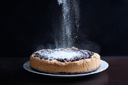 Berry pie cake from the cherries currants in a bowl fresh steaming hot sprinkle with powdered sugar background blurredの写真素材