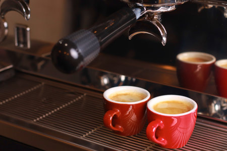 coffee cups stand inside the coffee machine on a grid, fresh coffee is poured inside the cupsの写真素材