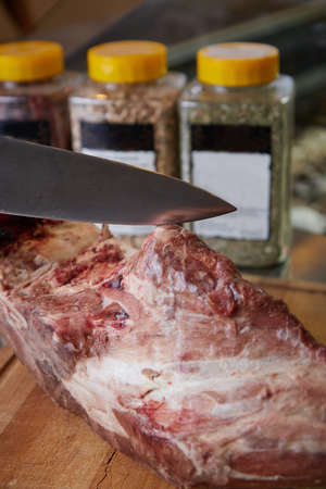 Juicy Fresh piece of meat on the table chef cuts with a knife spices and seasonings food blurred backgroundの写真素材
