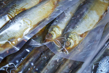 Vacuum packaging with smoked and dried fish on the counter in the window of the fish store food blurred backgroundの写真素材