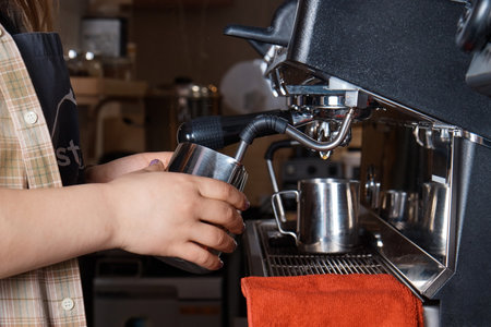 barista prepares and pours coffee into a mug on the coffee machine, close-up, hands of a woman, blurred backgroundの写真素材