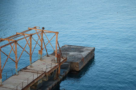 Concrete dock for ships at sea, old breakwater, rusty metal, water at sunset