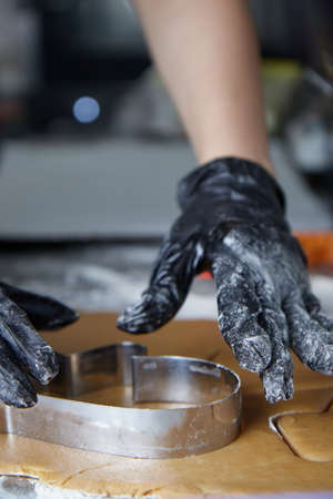 cook with gloved hands makes cookies using a dough mold