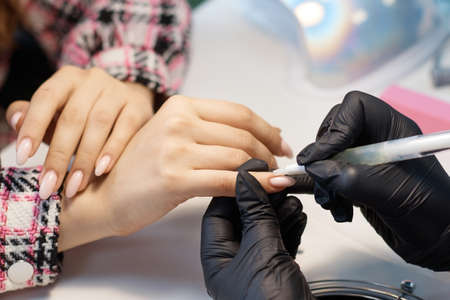 The master of nail service does a manicure, covers with varnish and increases nailsの写真素材