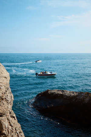 boat with passengers at sea, summer vacation, yacht trip in the middle of rocks and mountains, seascapeの写真素材