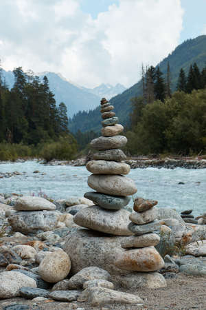pyramid of stones on the edge of a mountain river, mountains and mountain landscapeの写真素材