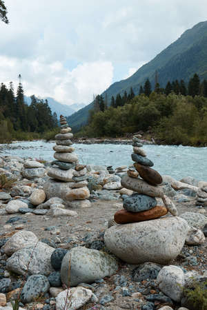 pyramid of stones on the edge of a mountain river, mountains and mountain landscapeの写真素材