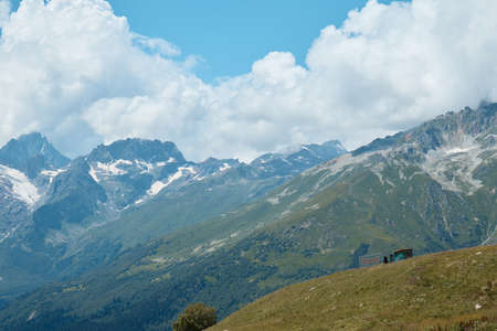 Landscape, mountain panorama, alpine meadows and mountain peaks in ice, a small house on the mountainsideの写真素材
