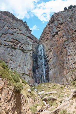 high waterfall, cliff and rocks, bottom view of a mountain waterfall, nature, landscape in the mountainsの写真素材