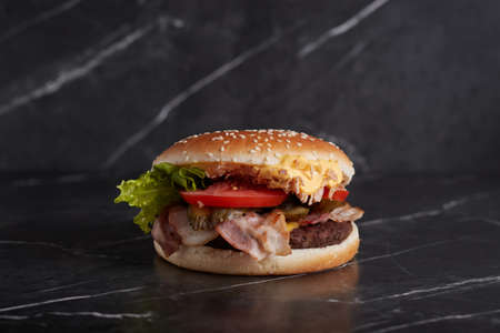 burger with meat and cheese on the table, american cuisine, close-up, tomato, dark background, marble,の写真素材